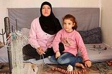 A mother and her child show the fishing net that the mother is making