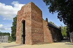 A small brick late-Gothic church with a ruined tower