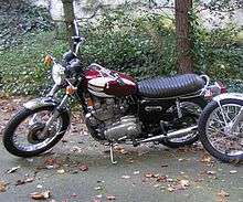 Red-and-white motorcycle, parked on fallen leaves