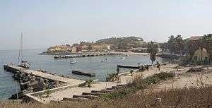 A picture with a beige dock in the foreground and a multicoloured city in the background.