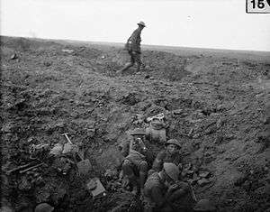 battlefield landscape with men resting in a shellhole in foreground