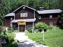 Photo of a wooden building with a winged heart logo over the door.