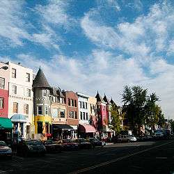 A dozen three to four story townhouses painted bright colors line a street