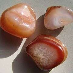 A group of tumble polished agates showing banding in red, orange and white with crystal interiors.