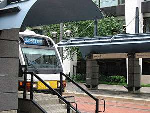 A southbound train emerging from a station featuring split side platforms.