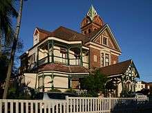 Colour photograph of the facade of a multi-storey brick house with a tower