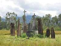 Half a dozen upright rough hewn stones about four feet high, some topped with stone crosses