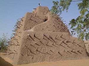 A large dirt mound shaped like a pyramid with sticks sticking out around it.