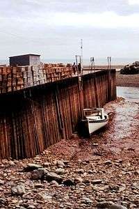 Photo of boat resting on bottom next to dock