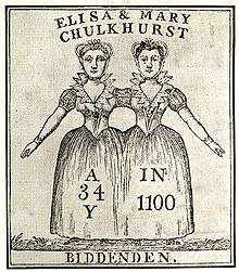 Two women, apparently joined at the shoulder. The women are wearing a single skirt between them. The women's facial features and hair colours are not identical.