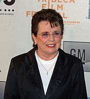 A brown haired women in a black jacket and white shirt