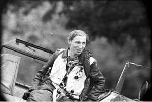 Mietusch stands inside his open aircraft cockpit wearing full flight gear.