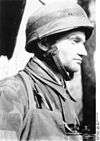 A man wearing a camouflage military uniform and steel helmet.