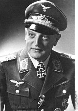 A man wearing a military uniform, peaked cap, and an Iron Cross displayed at the front of his uniform collar.