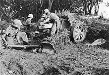 German soldiers in uniform with helmets, serving as crew of an anti-tank gun