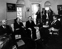 Picture of men wearing suits in a meeting.