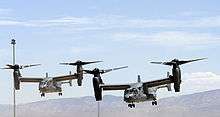  Two USAF CV-22s in a staggered pattern with their rotors vertical preparing to land at Holloman Air Force Base, New Mexico.