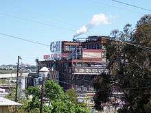 A large industrial building seen through trees.