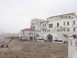 A picture taken in foggy weather depicting a white, contemporary building several storeys high.