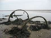 A derelict cart partly buried in the sand