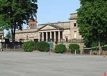 The frontage of a neoclassical buildings seen between trees