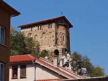 Southeast view of a narrow medieval church topping a cliff