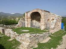 Southwest view of a partially ruined medieval church, with the eastern part mostly extant