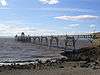 Metal pier standing on thin legs rising from the sea. Beach in the foreground