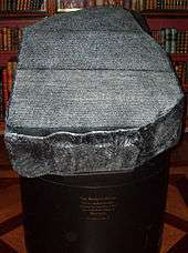 "Replica of the Rosetta Stone in the King's Library of the British Museum as it would have appeared to 19th century visitors, which was open to the air, held in a cradle that is at a slight angle from the horizontal and available to touch"