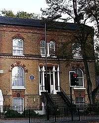 exterior of red bricked house, with blue plaque on front wall