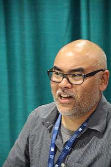 headshot of author with unbuttoned collared shirt and glasses