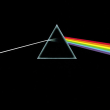 A prism refracting white light into a rainbow on a black background