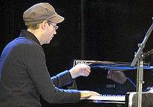 Braid wearing a cap and sitting at piano playing