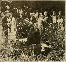 A man kneels over a dead body as a crowd watches.