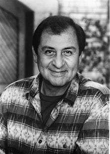 Black-and-white headshot of a man wearing a printed shirt with stripes.