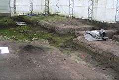 Trenches in bare earth; inside fabric-walled building