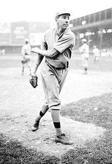 A black and white image of a man following through after throwing a baseball with his left hand