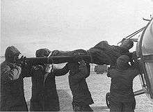 A wounded man is carried by soldiers onto a helicopter