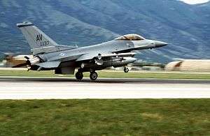 A fighter jet with AV marked on its tail takes off from a mountain runway.