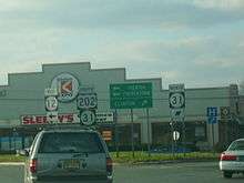 The view from a car windshield of signs for circle 12 circle 31 and U.S. 202 in the middle of a setting sun