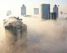 Skyscrapers, both near and far, soar above a dense layer of fog that keeps the ground hidden from view.