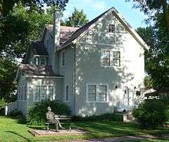 Two-story half-timbered house; statue of Norris seated on park bench in front