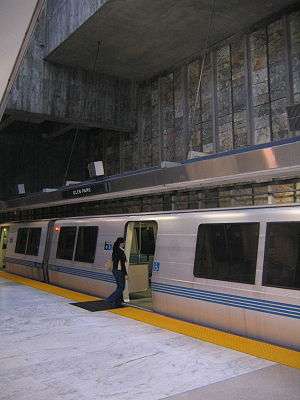 A near-empty station platform of a train station, with a person about to enter a train