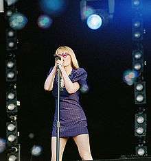 A woman on a stage singing into a microphone.