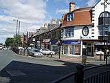 A terrace of stone fronted buildings, with a curved corner building fronted in white, from the mid-late 19th century