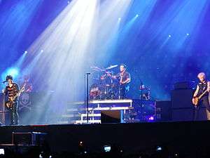 A color photograph of members of the group Green Day on stage with instruments