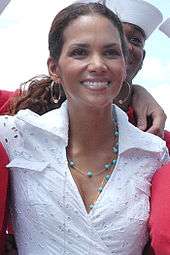 Head and shoulders shot of a smiling Berry with dark hair pulled back, wearing a lace shirt and turquoise necklace.