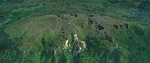 A long lightly glaciated mountain mass surrounded by vegetation.