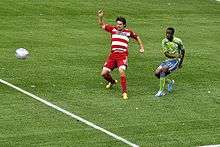 Zakuani vies against a Dallas player for the ball