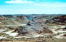 aerial view of canyon with mesas and creek in background